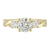 Round solitaire with smaller side diamonds atop a crisscross band with flowing diamond accents.